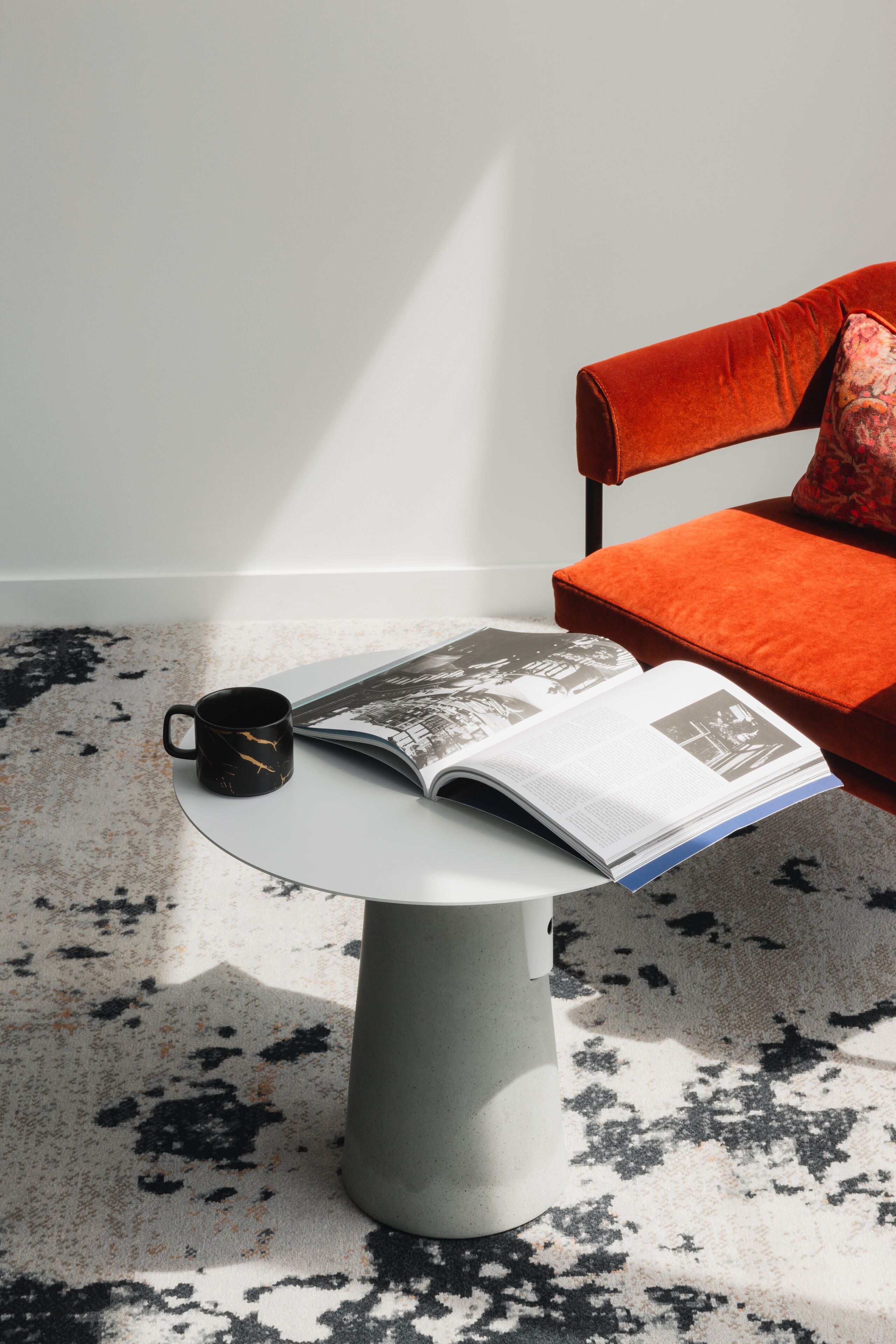 A modern room with a round table, a magazine, and a coffee cup.