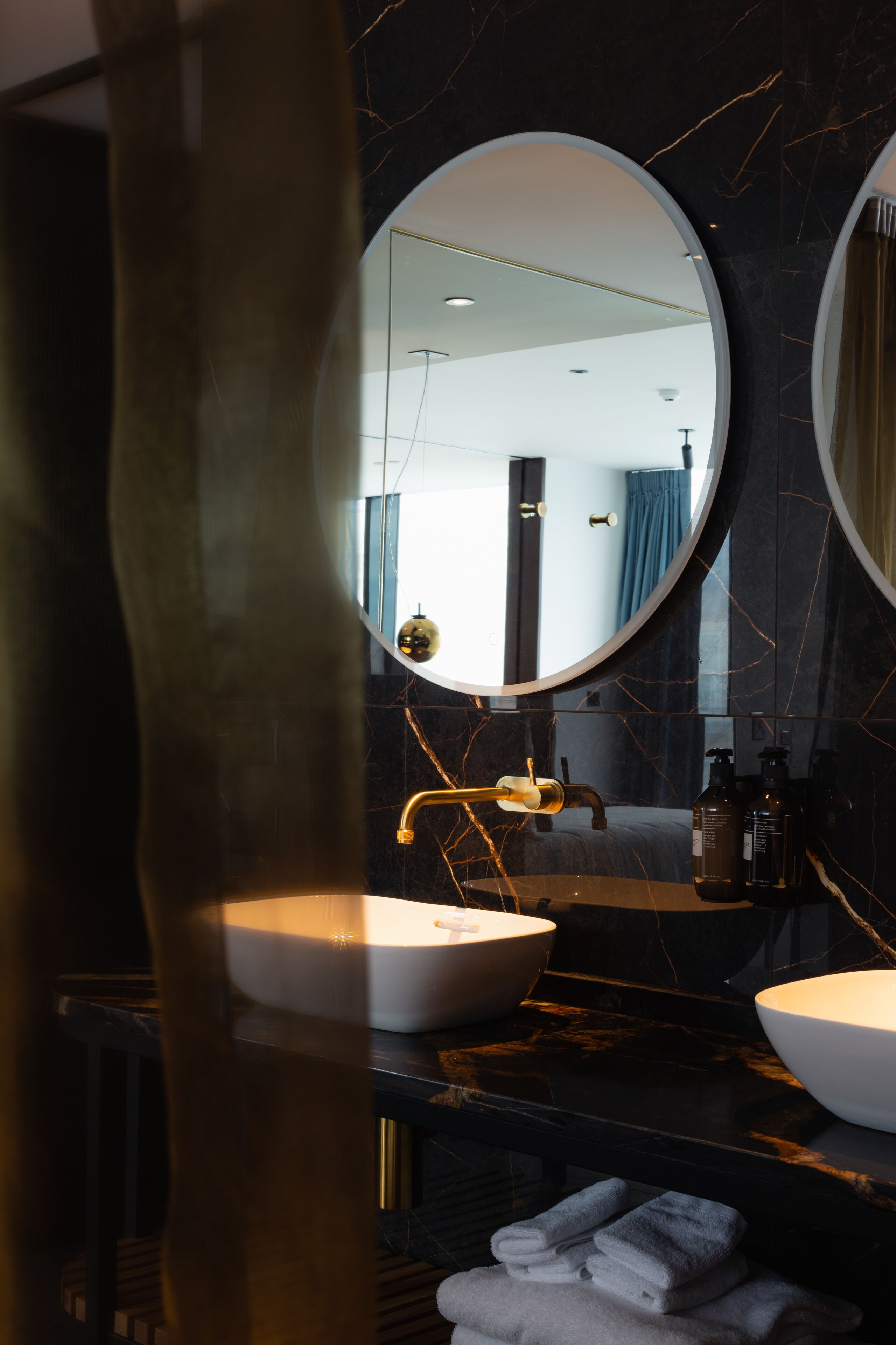 A bathroom with two sinks, a large mirror, and a towel rack with folded towels.