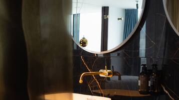 A bathroom with two sinks, a large mirror, and a towel rack with folded towels.