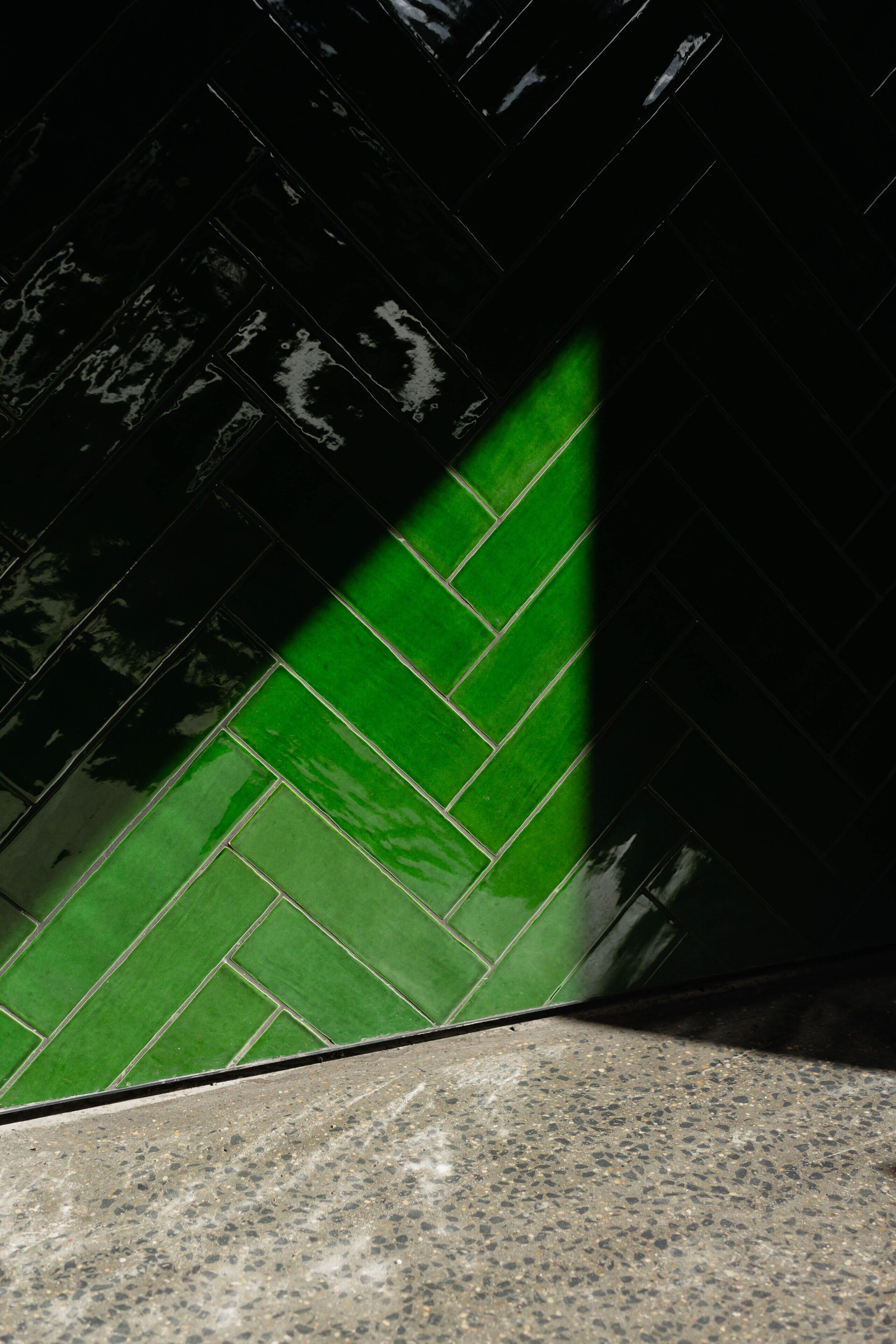 A corner of a room with a green herringbone-patterned wall and a speckled floor.