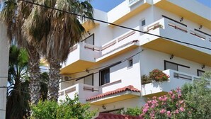 Un edificio de varios pisos con balcones, techo de tejas rojas y un letrero que dice 