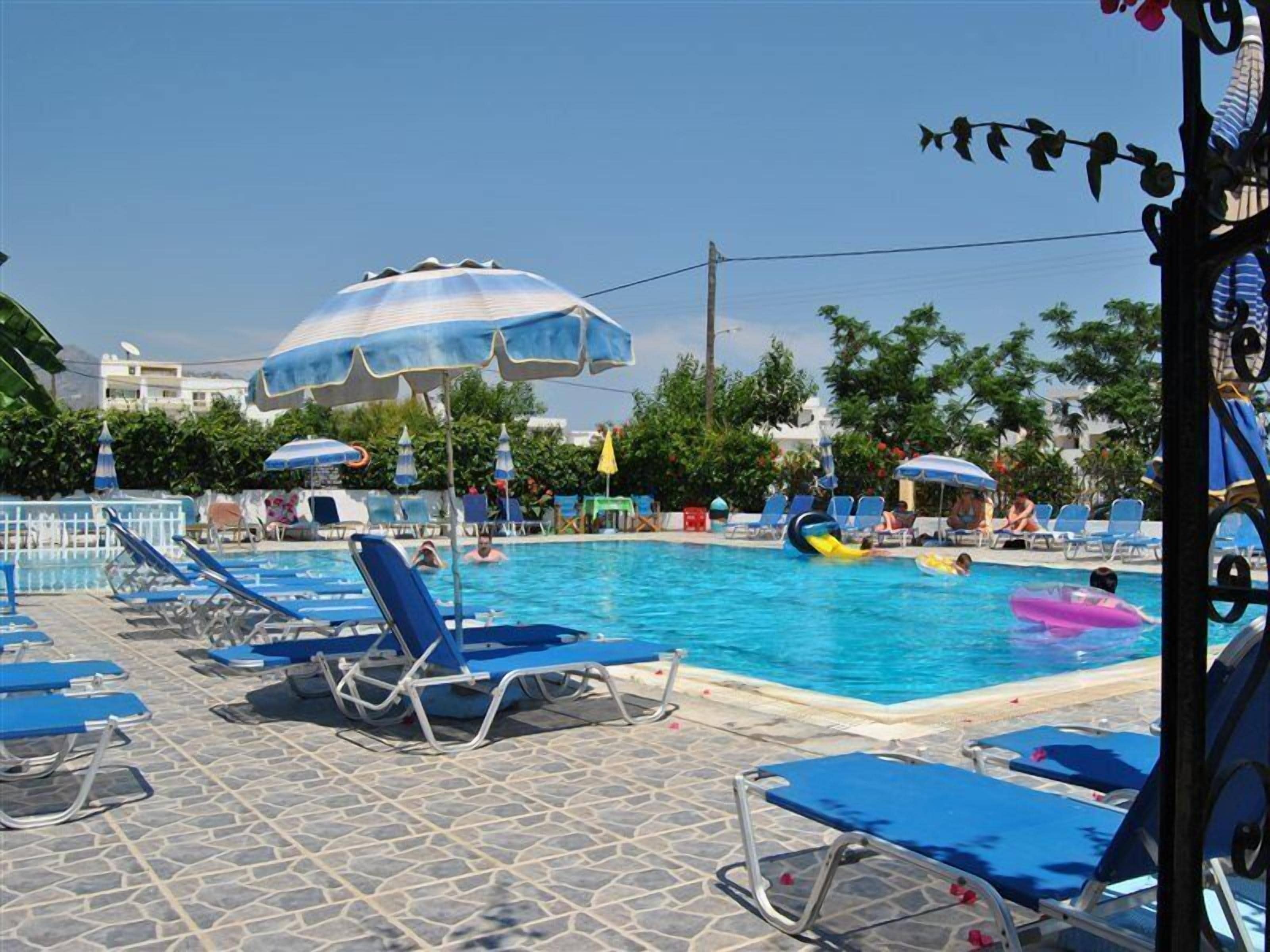 Una piscina con sillas de descanso azules y sombrillas.