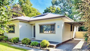 Ein Bungalow mit Veranda, Garage und kleinem Garten.