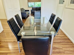 Un salón de conferencias con una mesa de vidrio y sillas negras, un sofá y un ventanal con vistas a zonas verdes.