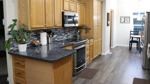 Una cocina moderna con armarios de madera, encimera de granito, electrodomésticos de acero inoxidable y una planta en maceta.