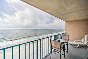 Enjoy the ocean view from this balcony with two chairs and a table.