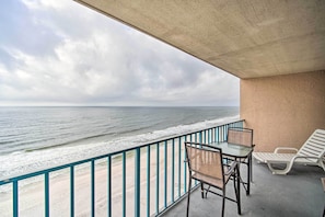 Enjoy the ocean view from this balcony with two chairs and a table.