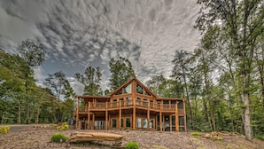 A large wooden cabin with a balcony, surrounded by trees and a forested area. - Serenity Peak | Mountain View | Close To Town | Paved | Dog Friendly (Blue Ridge)
