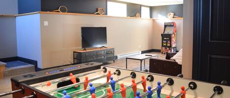A room with a foosball table, a television, and a vending machine.