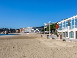 A beachside promenade with a modern building featuring large windows and a restaurant.