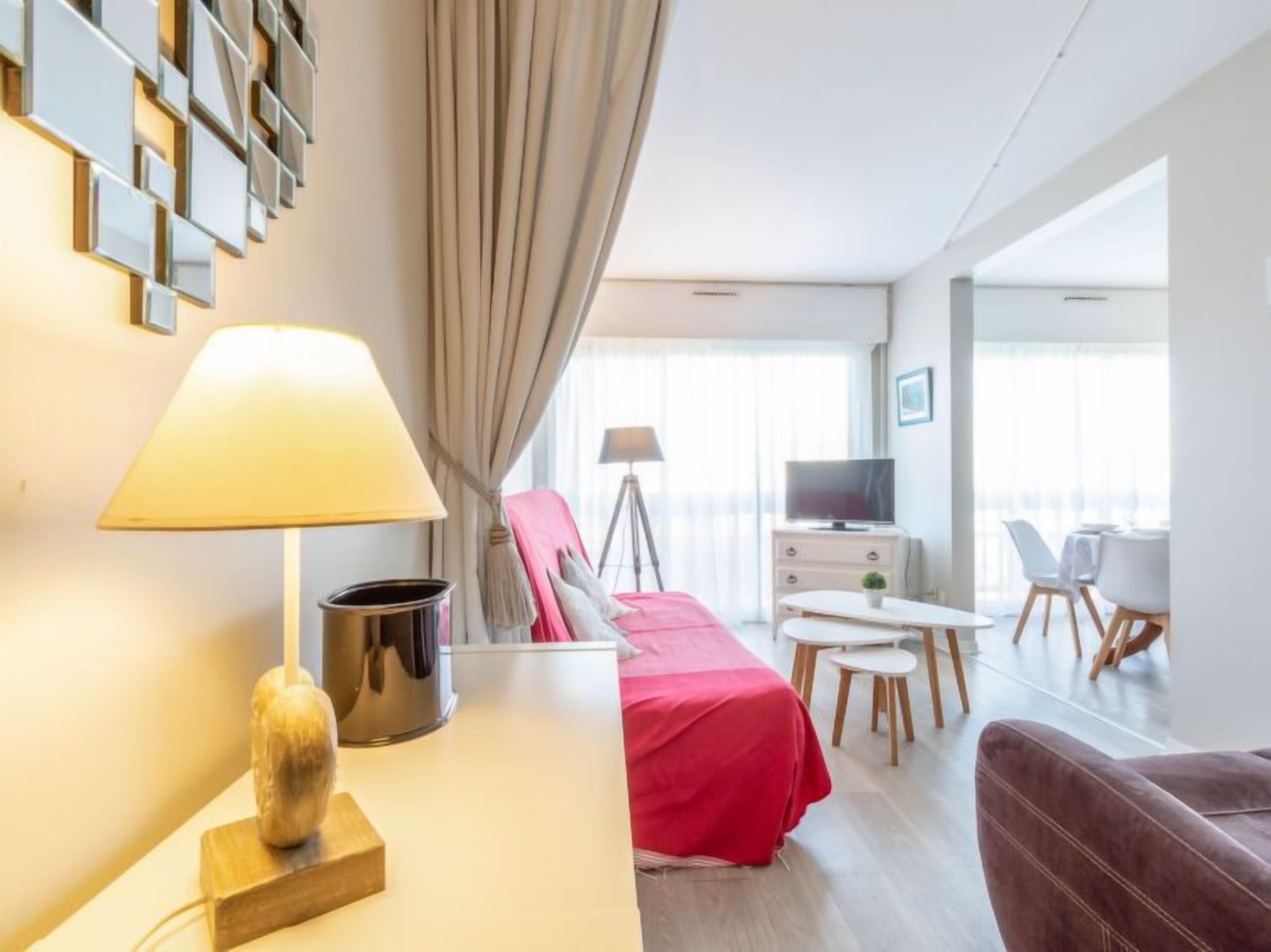 Une chambre d’hôtel moderne équipée d’un lit, d’un bureau avec une lampe, d’une télévision et d’un coin repas avec des chaises et une table.