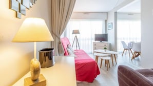A modern hotel room with a bed, a desk with a lamp, a TV, and a dining area with chairs and a table. - Le Maxime by Interhome (Sainte Maxime)