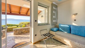 Ein modernes Zimmer mit einer Couch, einem kleinen Tisch, einem Fenster mit Aussicht und einer Tür zu einem Außenbereich.
