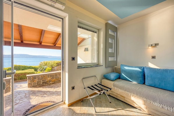 Ein modernes Zimmer mit einer Couch, einem kleinen Tisch, einem Fenster mit Aussicht und einer Tür zu einem Außenbereich.