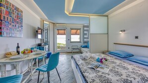 Ein modernes Schlafzimmer mit Bett, Schreibtisch mit Stühlen, Esstisch mit Stühlen und einem Balkon.