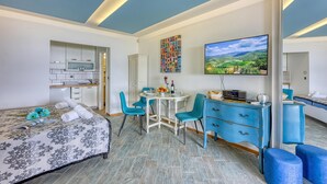 Een moderne hotelkamer met een bed, een zithoek, een televisie en een spiegel.