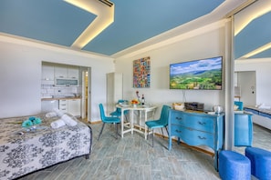 Une chambre d’hôtel moderne équipée d’un lit, d’un coin repas, d’une télévision et d’un miroir.