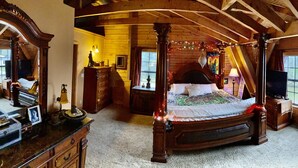 A four-poster bed with a canopy, wooden walls, a desk with a chair, and a television.