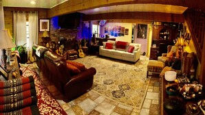 A cozy living room with a fireplace, a sofa, a red armchair, and a coffee table with decorative items.