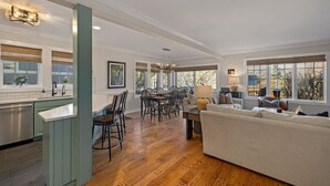 A spacious living area with a dining table, a sofa, and a kitchen area with a sink and cabinets.