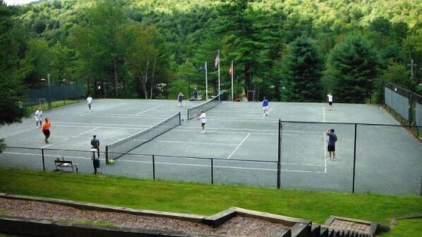 An outdoor tennis court surrounded by trees.