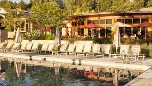 A swimming pool with lounge chairs, a restaurant with outdoor seating, and a building with a traditional architectural style.