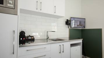 A modern kitchen with white cabinets, a stainless steel sink, and a coffee machine.