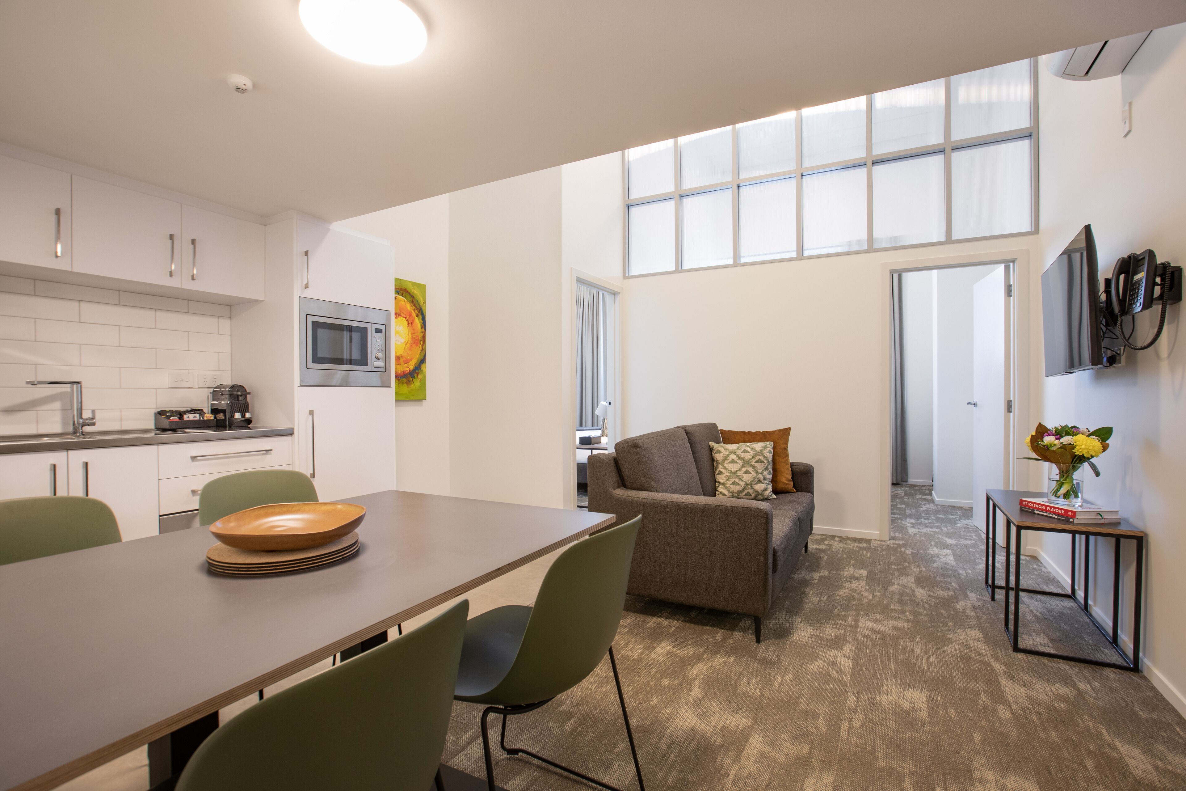 A modern kitchen with white cabinets, a microwave, and a dining area with a table and chairs.