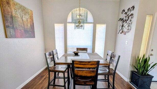 A dining area with a wooden table and chairs, a chandelier, and a large window with blinds. - Whole house with a Texas sized lot (Pflugerville)