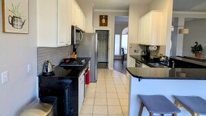 A modern kitchen with white cabinets, a stainless steel refrigerator, a gas stove, and a trash can. - Whole house with a Texas sized lot (Pflugerville)