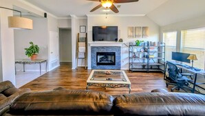 A living room with a fireplace, leather sofa, and a TV. - Whole house with a Texas sized lot (Pflugerville)