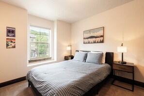 Una camera da letto con un letto, due comodini, una finestra e un quadro appeso al muro.