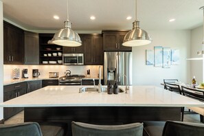 Una cucina moderna con mobili in legno scuro, elettrodomestici in acciaio inossidabile e una grande isola con sgabelli da bar.