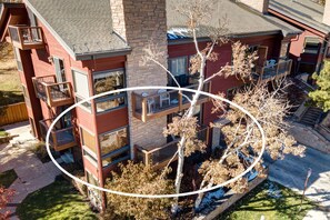 A multi-story building with balconies, a stone facade, and a tree in the foreground. - Walk to Main Street, Shopping & Restaurants! Year-Round Recreation at Park City Silver Cliff 108 (Park City)