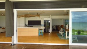 Una cocina moderna con una isla central, un área de comedor con vistas y un amplio ventanal corredizo que da a un balcón.