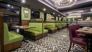A restaurant with green booths, wooden tables, and a patterned floor. - T24 Retro (Mumbai)