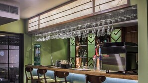 A bar area with a counter, stools, hanging glasses, and a coffee machine. - T24 Retro (Mumbai)