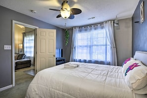 Relax in this serene bedroom with a large bed, ceiling fan, and mounted TV.