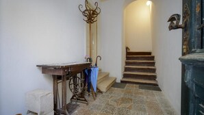 A hallway with a wooden table, a mirror, and a staircase leading to an upper floor. - Apartment Klara (Dubrovnik)