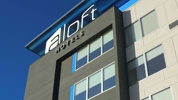 A modern hotel building with a prominent logo and name on the facade.