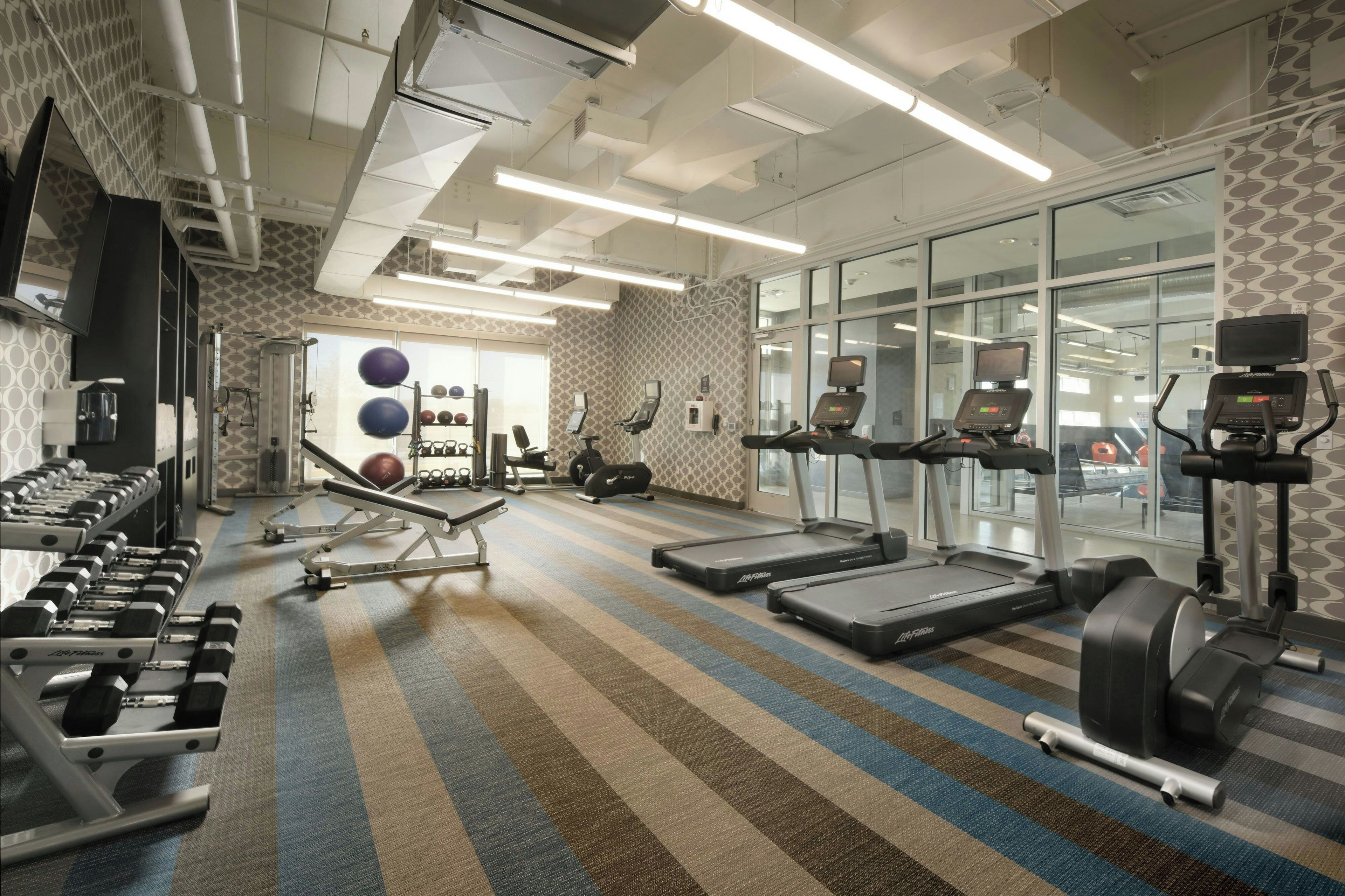 A gym with treadmills, weight machines, and exercise balls.
