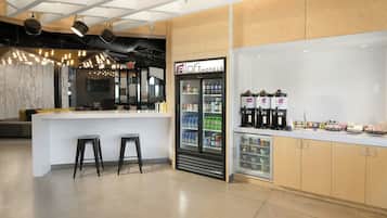 A modern bar area with a minibar, stools, and a refrigerator stocked with beverages.