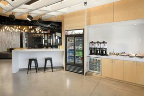 Un área de bar moderna con un mini bar, taburetes y un refrigerador lleno de bebidas.