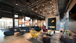 A modern lounge area with sofas, armchairs, and a coffee table. - Aloft by Marriott Lubbock (Lubbock)