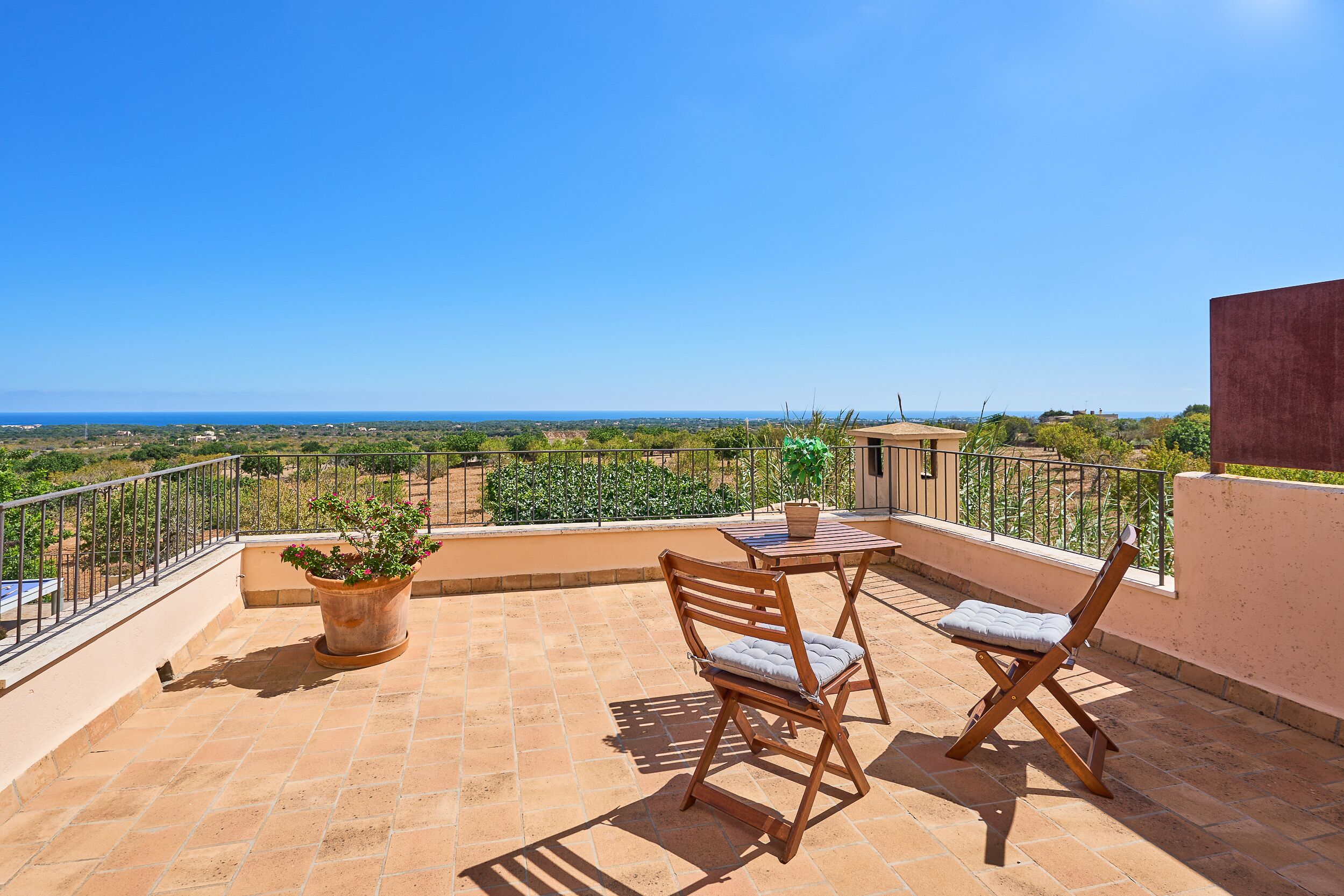 Eine Terrasse mit Tisch und Stühlen, einem Blumentopf und Blick auf die Landschaft.