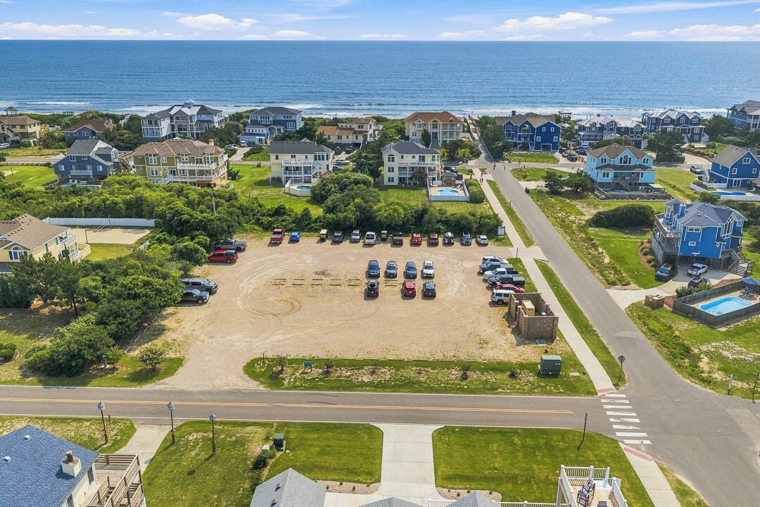 Une zone résidentielle côtière comprenant des maisons, un parking et une route.