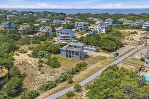 A coastal residential area with houses, a beach, and a clear view of the ocean. - Sunbelievable | 930 ft from the beach | Private Pool, Hot Tub, Dog-Friendly | Corolla (Corolla)