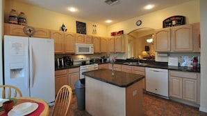 A kitchen with wooden cabinets, a central island, a refrigerator, a microwave, and a sink. - The Lake House! 7Br 4.5ba with private pool! (Kissimmee)