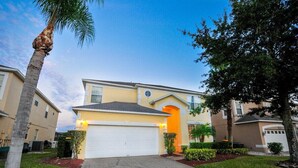 A residential house with a garage, a well-maintained lawn, and a palm tree. - The Lake House! 7Br 4.5ba with private pool! (Kissimmee)