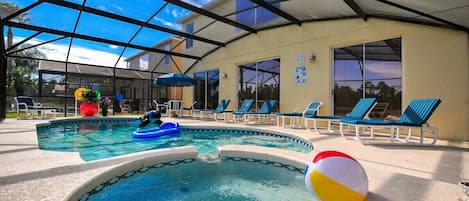 Une piscine extérieure couverte, dotée de chaises longues et d’un ballon de plage.